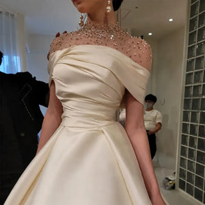 Robe orientale satinée ivoire à col haut orné de perles