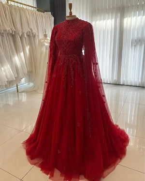 Robe longue rouge à cape brodée présentée en boutique
