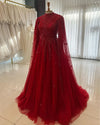 Robe longue rouge à cape brodée présentée en boutique