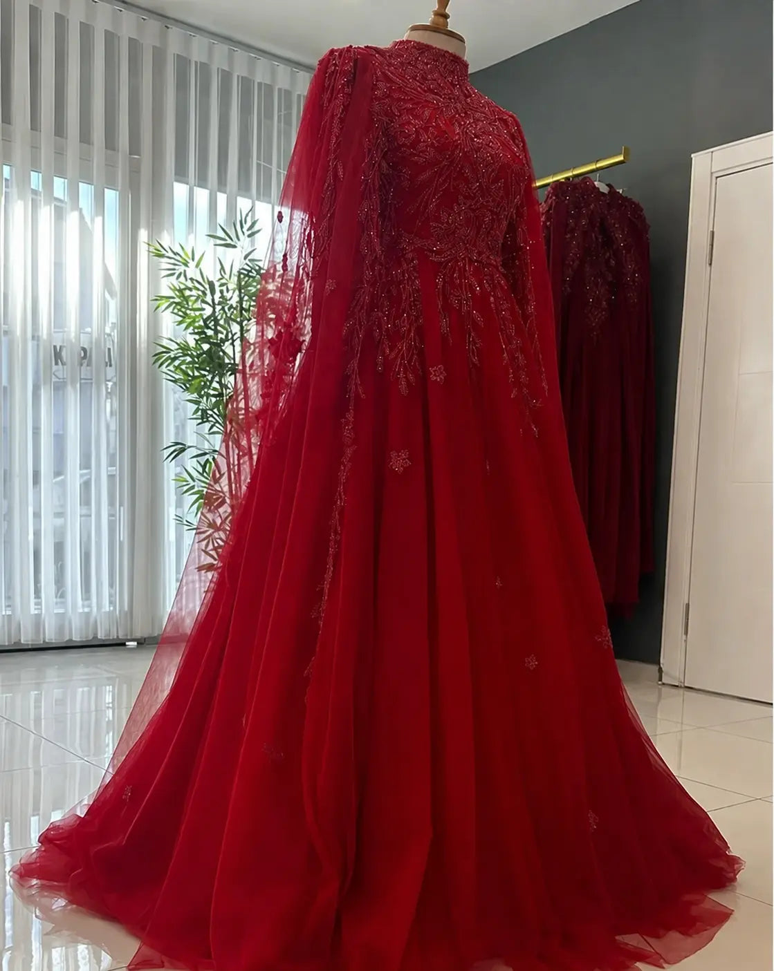 Robe rouge de cérémonie à cape en tulle brodé vue de trois quarts